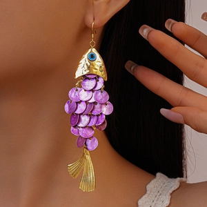 Detailed close-up of fish-shaped earrings with purple scales worn on a model