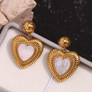Détail macro de boucles d'oreilles cœur en or 18K avec nacre blanche dans un coffret