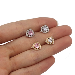 Dettaglio ravvicinato di orecchini a cuore in zircone con perle indossati sulle dita