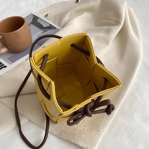 Yellow hand-woven PU leather bucket bag with drawstring closure and brown shoulder strap
