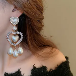 Eleganti orecchini a cuore con perle e strass indossati da una modella donna