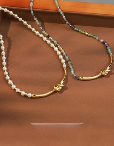 Detail of colorful gemstone and pearl beaded necklaces with gold metal tube accent