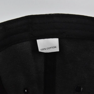 Close-up of the internal label showing 100% cotton material on the black baseball cap