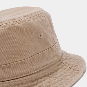 Détail d'un bob en toile lavée montrant les lignes de couture et les œillets brodés