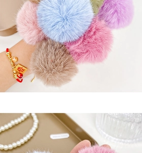 Detail of colorful plush balls hair ties with red strings and gold character charms