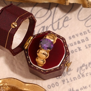 Macro detail of oval purple gemstone ring in a vintage hexagonal velvet jewelry box