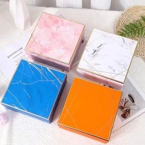 Overhead view of four marble pattern gift boxes in pink, blue, white, and orange colors