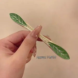 Detail showing a 14.9cm vintage gold hair stick with green enamel leaves for buns