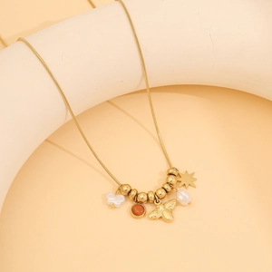 Golden bee pendant necklace with pearls and star charms on a geometric display stand