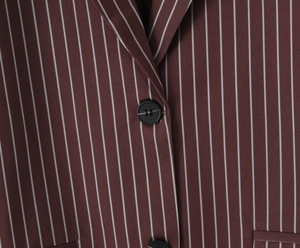 Detail of dark brown pinstripe blazer showing crisp lapel cut and black button texture