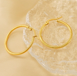 Detail of 18K gold-plated titanium steel hoop earrings with textured thread design