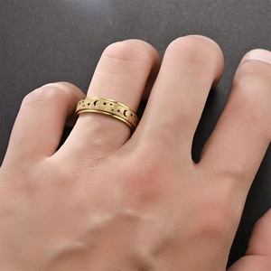 Close-up of golden spinning ring with moon and star patterns worn on a finger