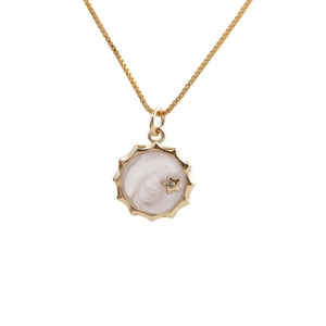 Detailed close-up of a gold-plated sun pendant with white marble enamel and star inlay