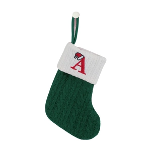 Detailed knit texture of a green Christmas stocking with red embroidered letter A and hat