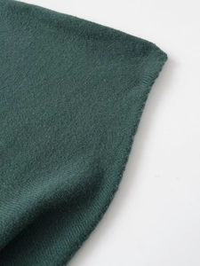 Macro shot of fine knit dark green wool fabric texture with professional seaming detail