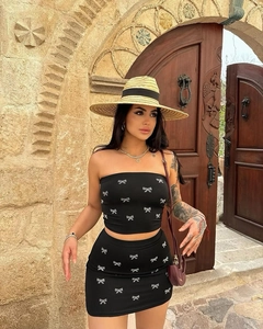 Detail of black tube top and skirt set with white bow prints in a stylish outdoor setting