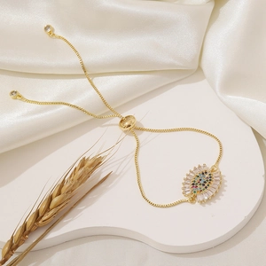 Adjustable gold bracelet featuring a colorful cubic zirconia eye charm on a silk background