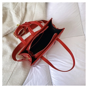 Internal view of red tote bag showing black lining, zipper pocket and wide strap