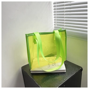 Close-up of a neon green transparent PVC tote bag with nylon straps on white books