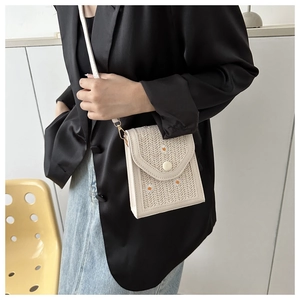 Detail of woven straw crossbody phone bag with embroidered daisy floral patterns