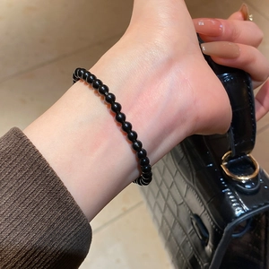 Detailed view of obsidian beaded bracelet with glossy finish on a woman wrist