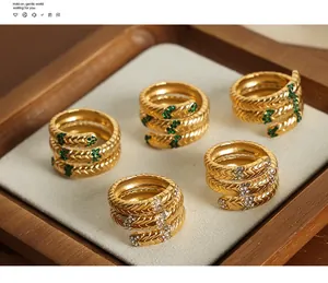 Nahaufnahme von fünf schlangenförmigen Goldringen mit grünen Edelsteinen und Diamanten