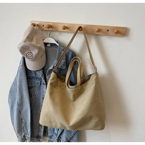 Khaki canvas tote bag hanging on wooden wall hook with jacket in a lifestyle scene
