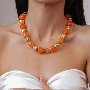 Close-up of orange acrylic and gold geometric beads on a stylish women's necklace