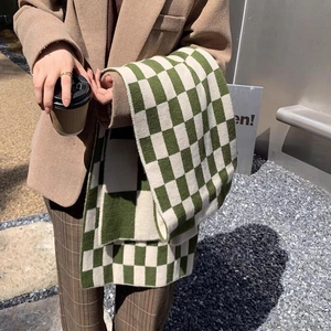 Stylish green and beige checkered cashmere scarf worn over a khaki blazer in outdoor setting