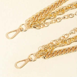 Detail of multi-layered gold metal pant chain with lobster clasps and polished finish
