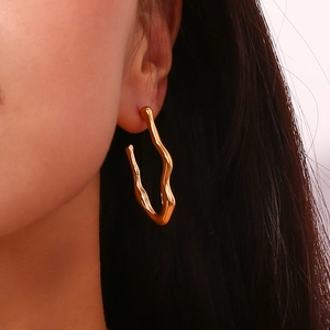 Detailed close-up of 18K gold plated stainless steel wavy hoop earring on model