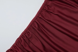 Dettaglio del tessuto a maglia bordeaux con design arricciato su un abito aderente