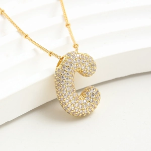 Collana con ciondolo lettera C placcata oro e zirconi cubici su sfondo bianco