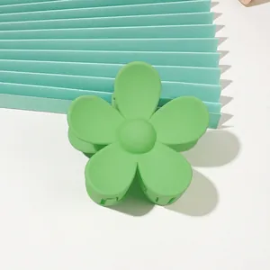 Detail of a matte pale green flower hair claw clip on a matching mint green background