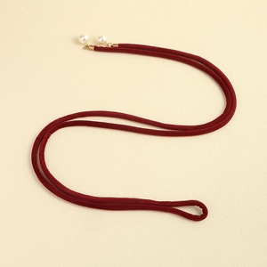 Detailed close-up of dark red velvet waist belt with white pearl beads and gold accents