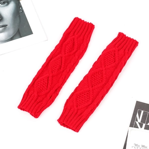 Detailed view of red cable knit arm warmer with ribbed cuffs on white magazine background
