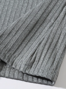 Détail du tissu en maille côtelée grise montrant la texture douce et la couture de l'ourlet