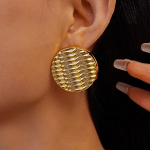 Close-up of golden acrylic round earrings with ripple texture worn by a model