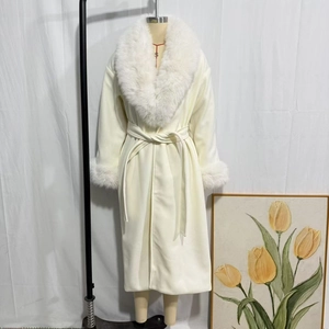 Dettaglio del cappotto lungo bianco con ampio collo in pelliccia e cintura abbinata