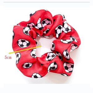 Detail shot of a red soccer pattern satin scrunchie with a 5cm width measurement scale