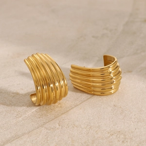 Polished gold stainless steel C-shape croissant hoop earrings on stone background