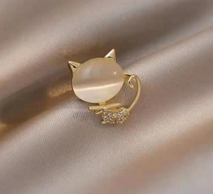Macro shot of gold cat brooch with opal stone and sparkling zircon details on silk