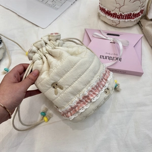 Close-up of quilted drawstring pouch with lace trim, rabbit embroidery and colorful beads
