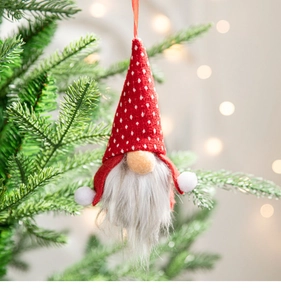 Close-up of a Christmas gnome ornament with a red polka dot hat on a pine branch