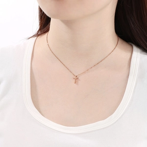 Close-up of minimalist gold cross necklace pendant on model neck jewelry detail