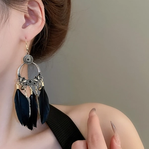 Gros plan détaillé des boucles d'oreilles bohèmes avec plumes noires et base argentée