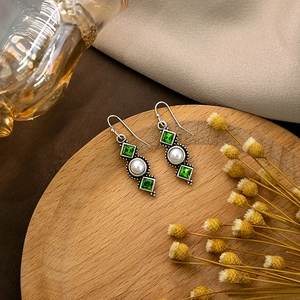 Detail of vintage silver hook earrings with green stones and round white pearls