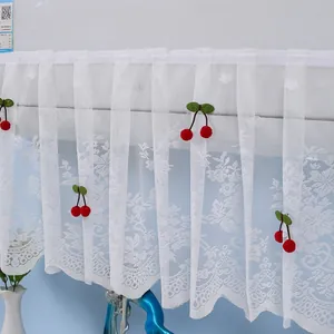 Close-up of white lace curtain with 3D red cherry embroidery and scalloped edges