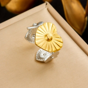 Macro shot of two-tone open heart ring with gold radial texture and silver band