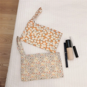 Detailed macro view of floral cotton storage bags with zipper and wrist strap handles